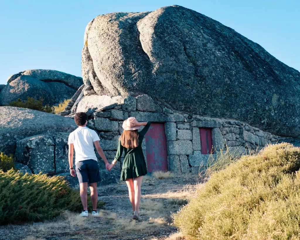 Casal a visitar a Casa do Penedo na Serra da Estrela, símbolo turístico e arquitetónico em pedra, experiência romântica em contacto com a natureza