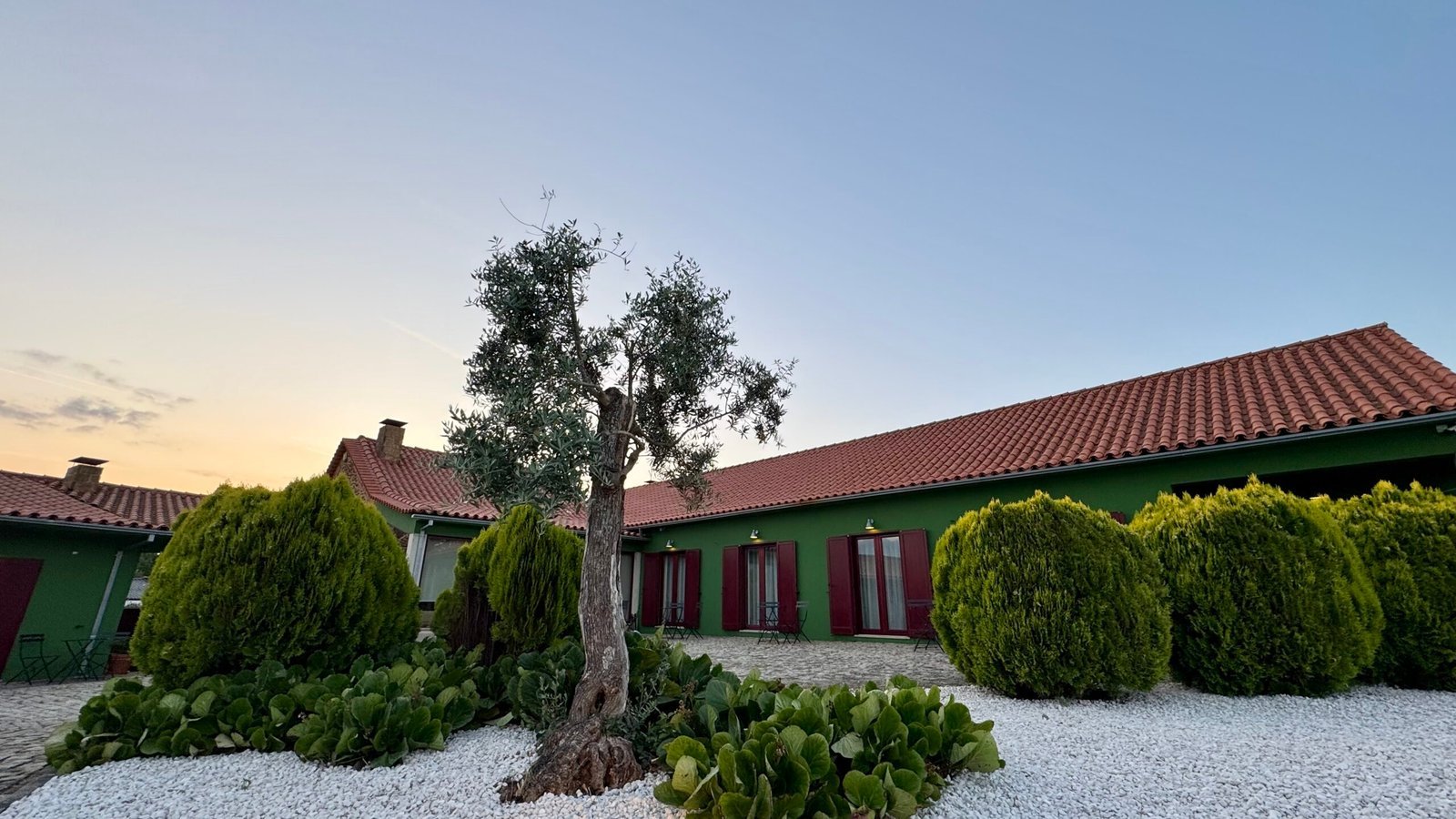 Vista exterior dos alojamentos Raízes da Vinha, Matias Nature, na Serra da Estrela, com jardim cuidado e arquitetura rural