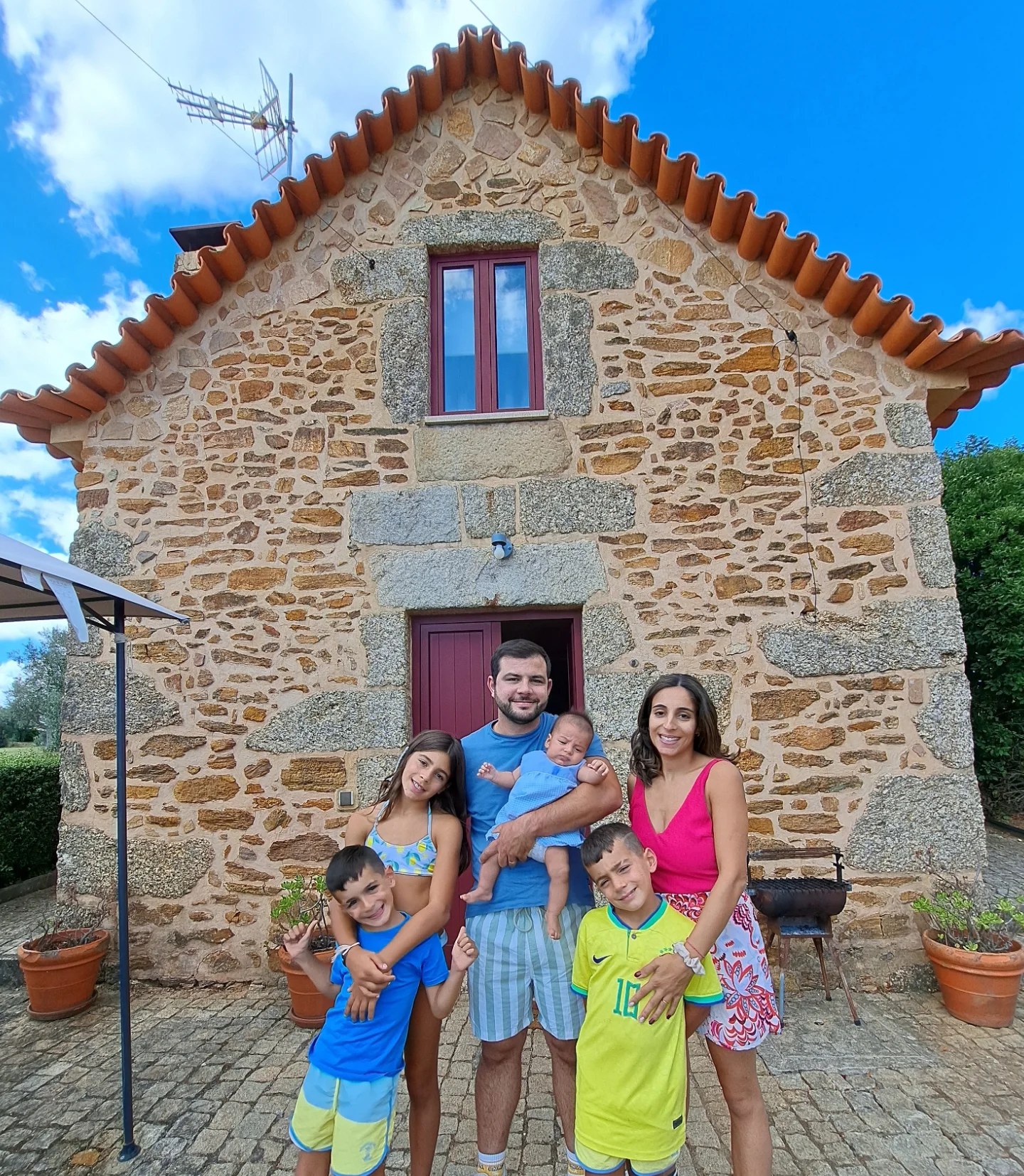 Família em frente a casa de pedra típica da Serra da Estrela, representando alojamentos rurais familiares da Matias Nature